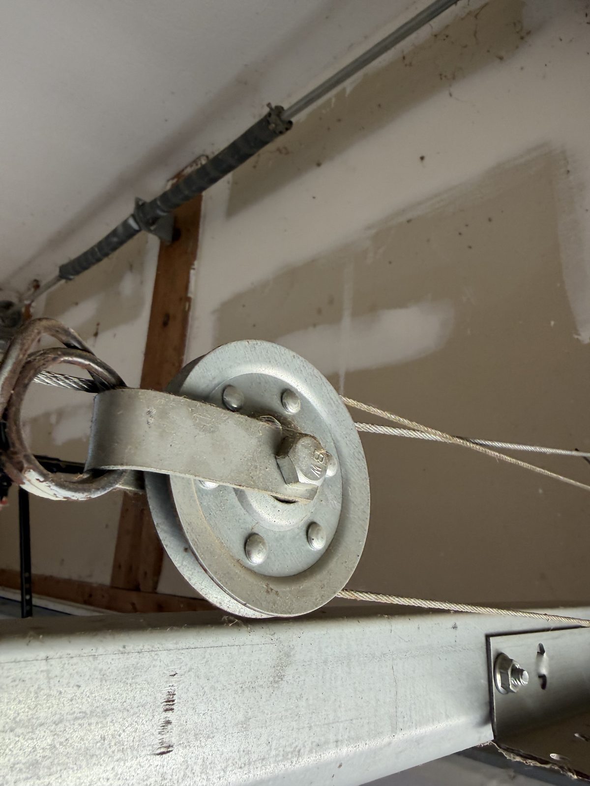 Garage door lift cable correctly routed through the idler pulley