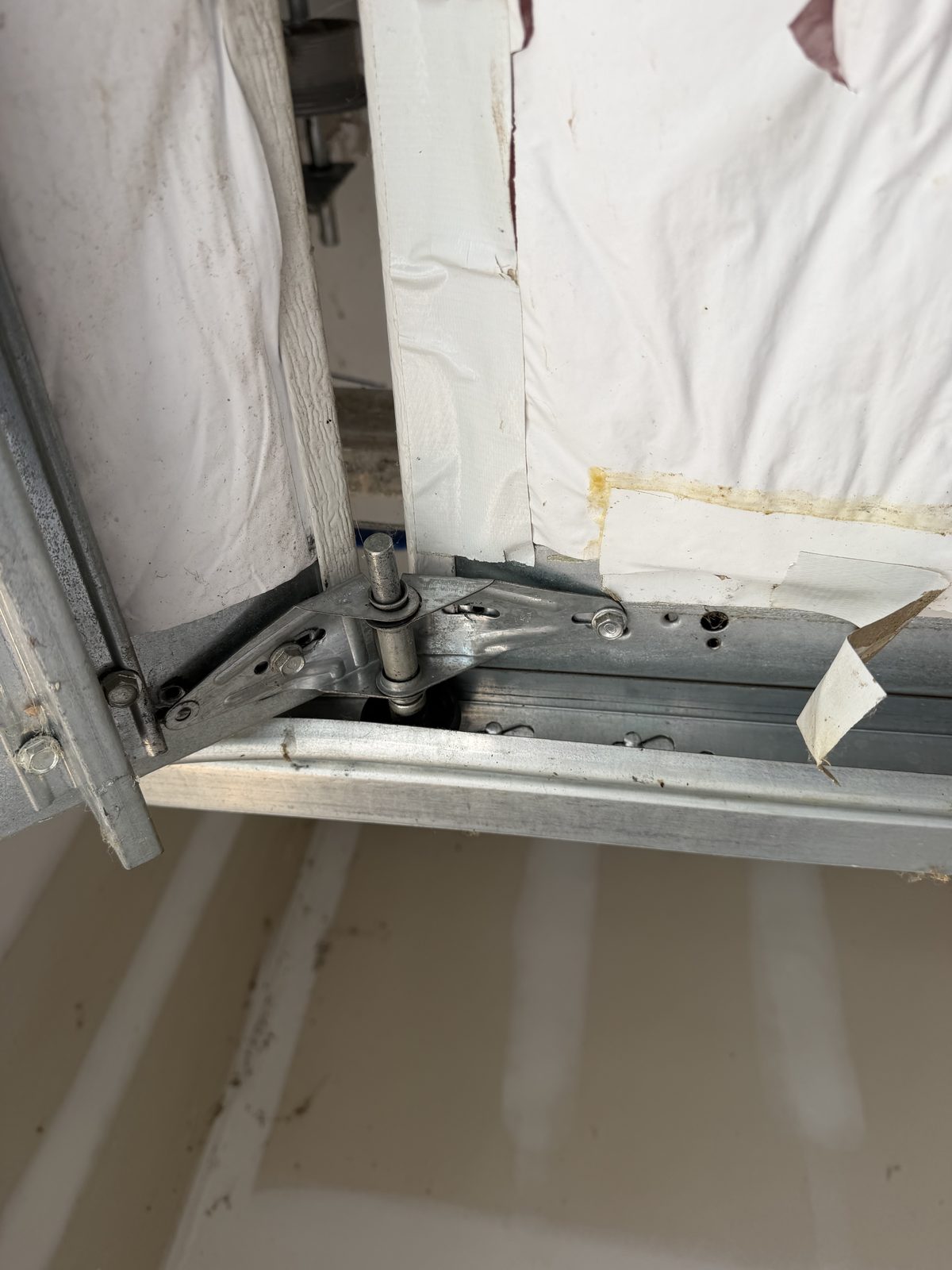 Bent garage door hinge with missing screws found during a tune-up