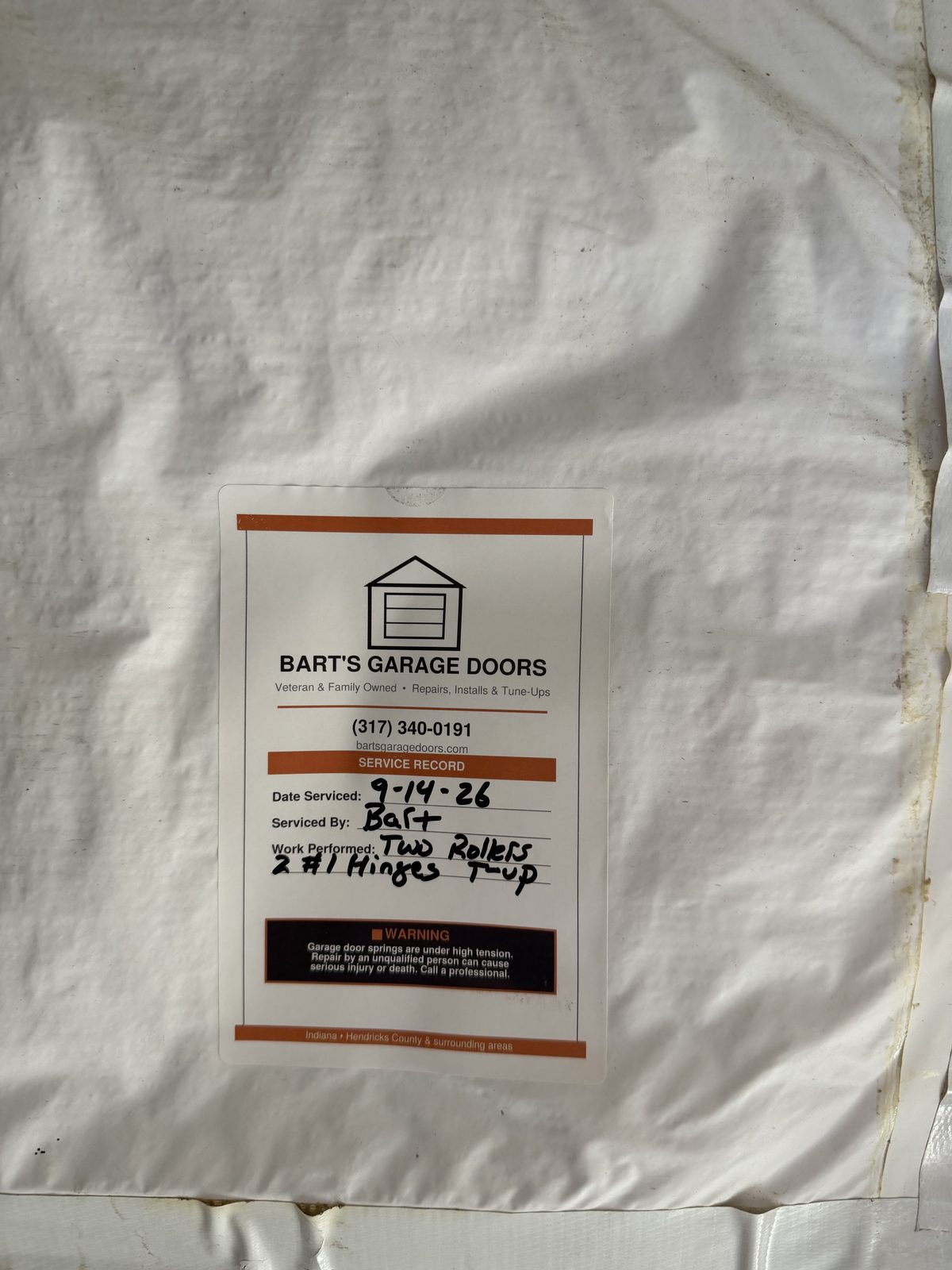 Bart's Garage Doors service record tag documenting a roller and hinge tune-up completed September 14, 2026