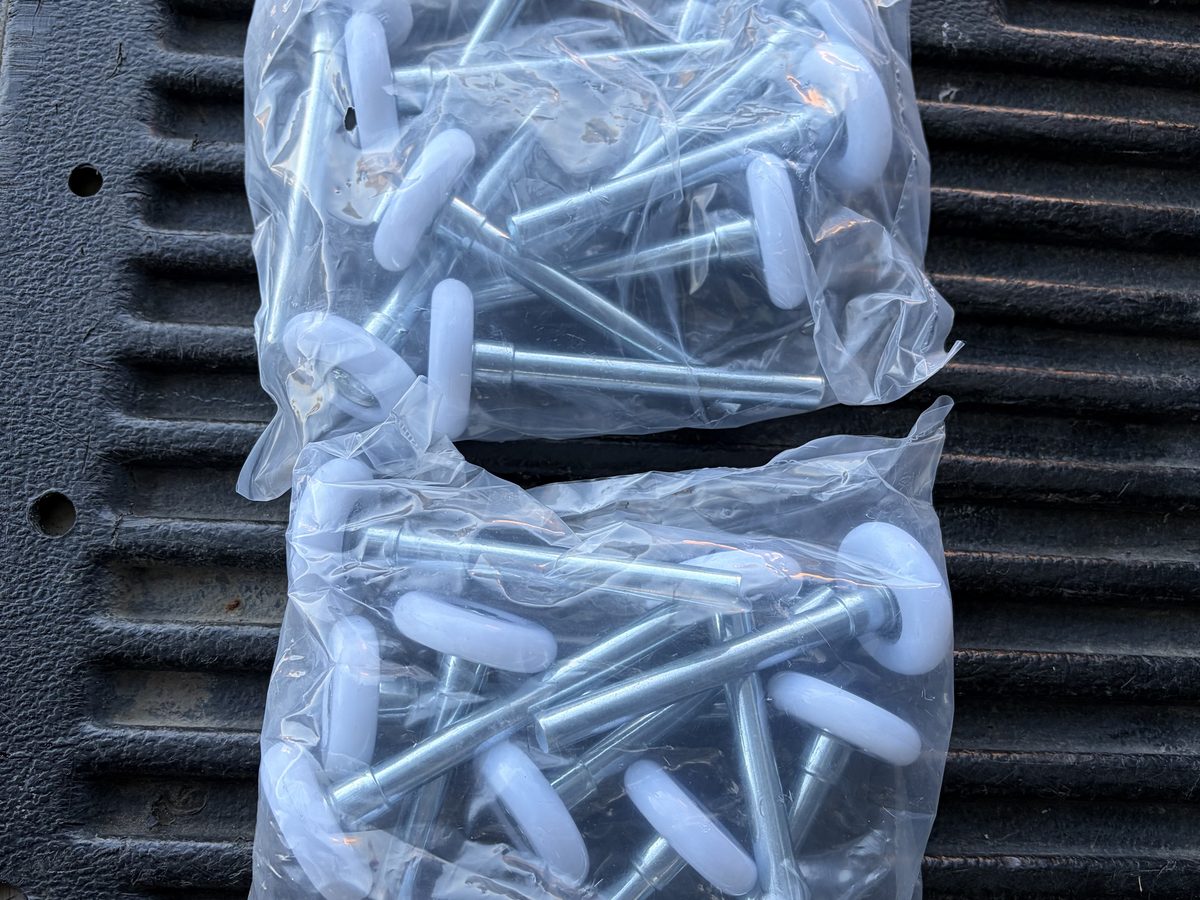 Bags of new white nylon garage door rollers stocked on the truck